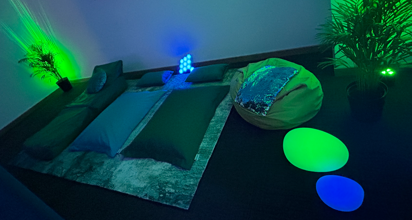 Blankets and cushions on the floor of a darkly lit room with green light