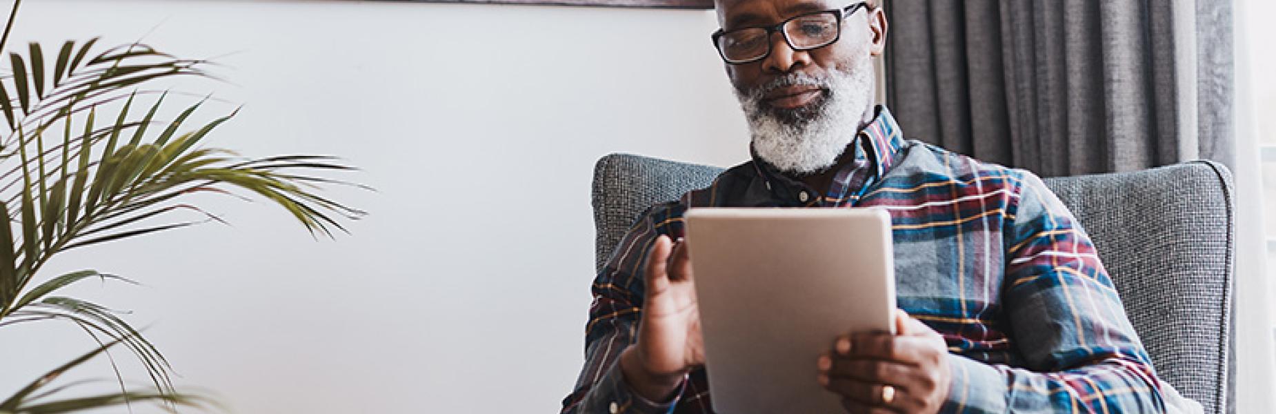 Man sitting in an armchair viewing a digital tablet