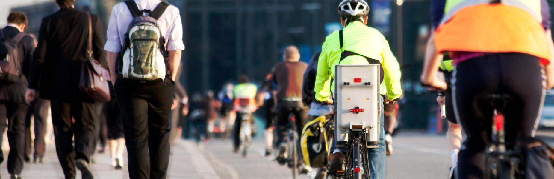 Commuters walking and cycling along a busy street