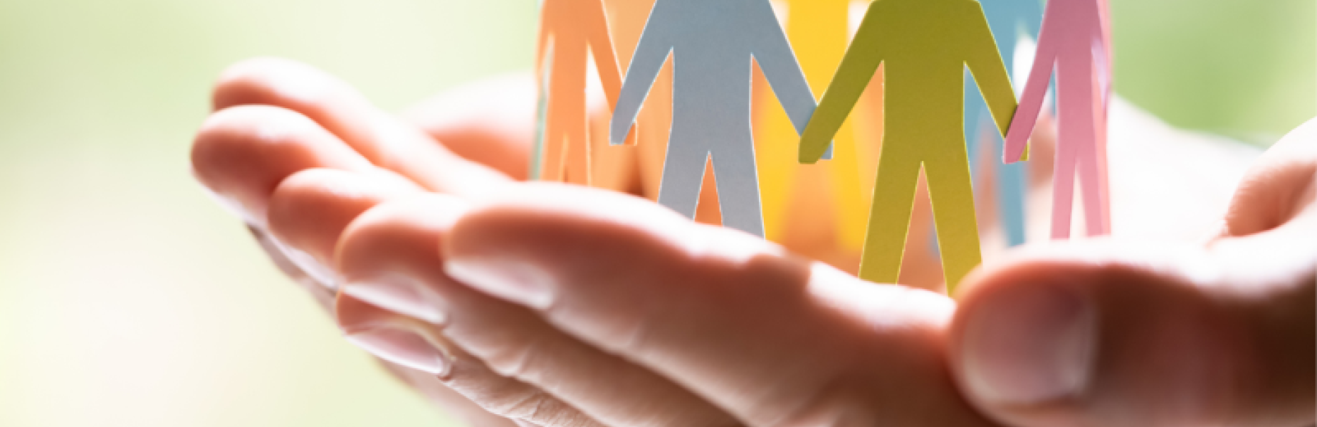 Dwylo’n dal yn ofalus grŵp o ffigurau papur lliwgar wedi’u torri allan, yn sefyll mewn cylch.