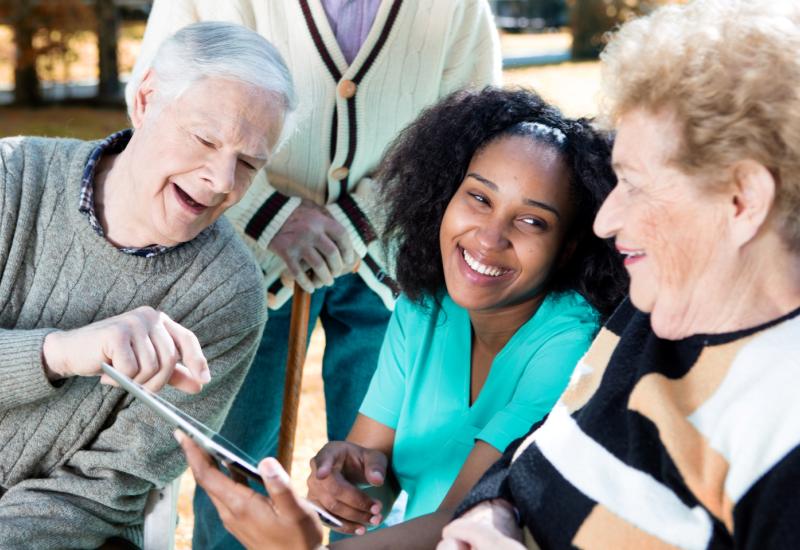 Two older people learning to use a tablet with a health practitioner